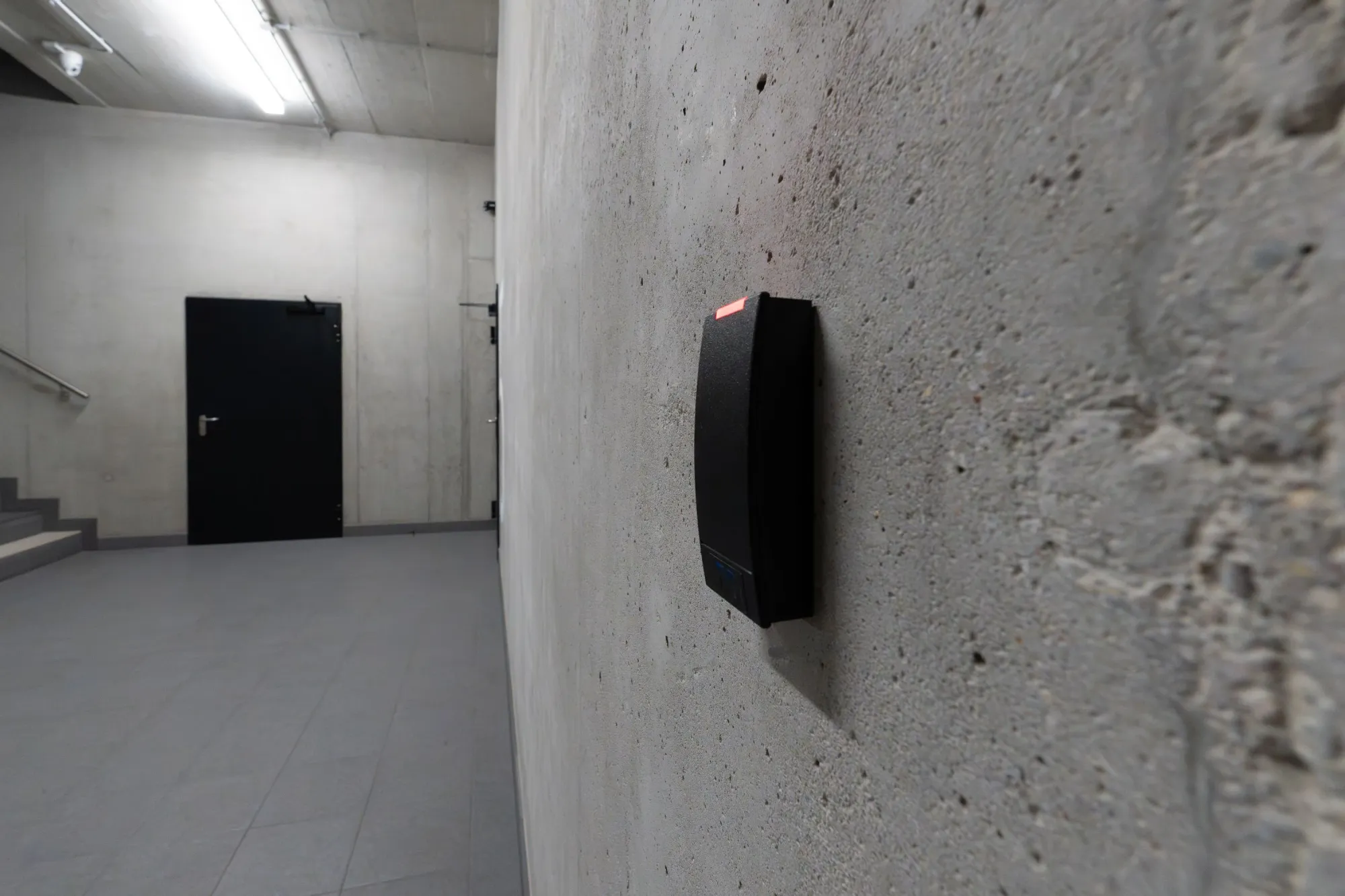 Black card reader mounted on a concrete wall in a stairwell