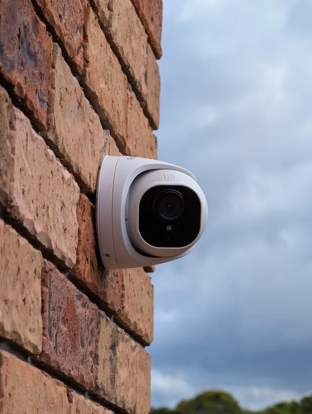 White dome security camera mounted on a brick wall corner