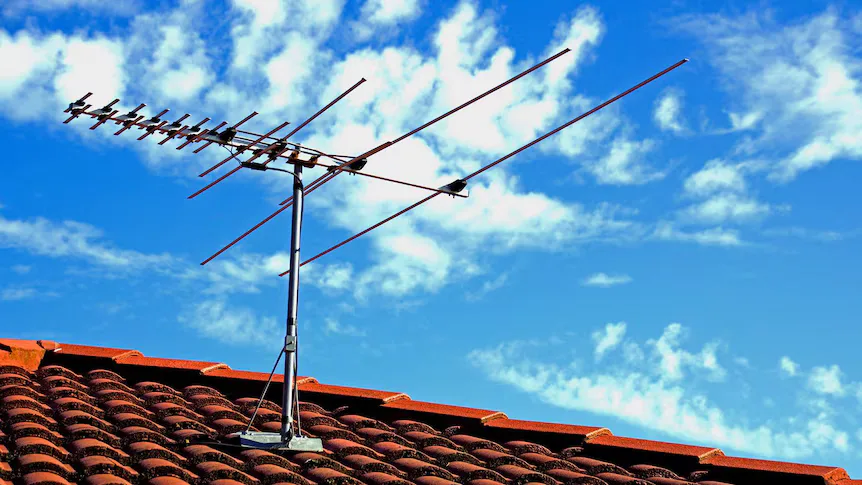 TV antenna mounted on a terracotta tiled roof against a blue sky