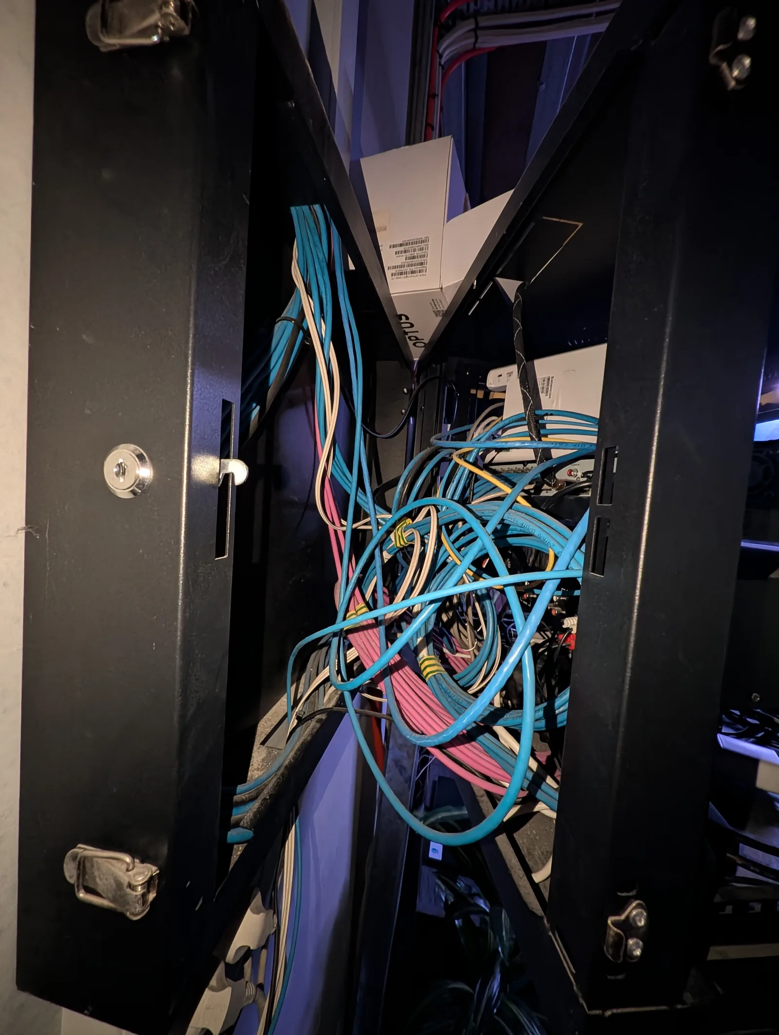Tangled data cabling behind the panel of the same cabinet