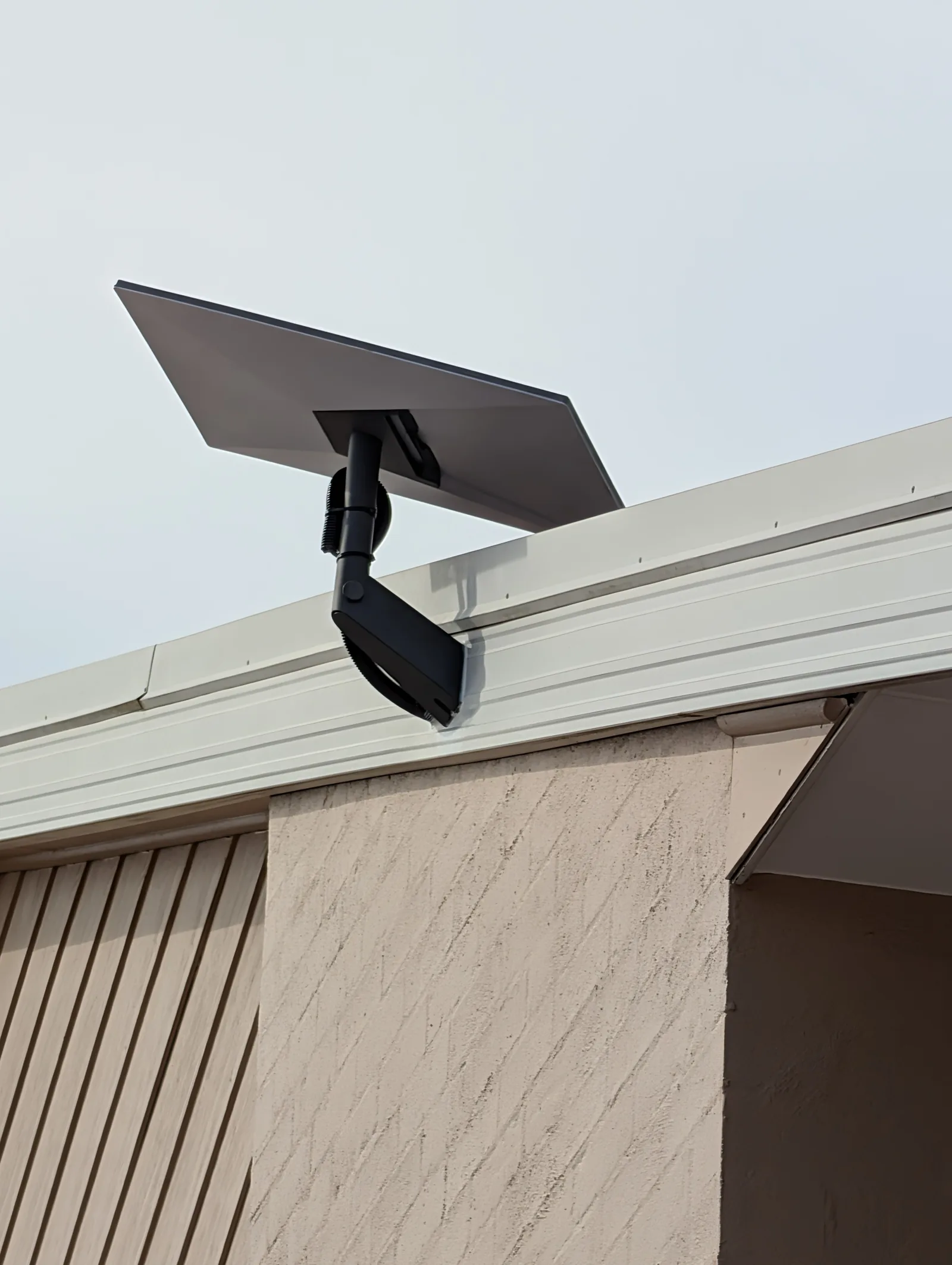 Starlink dish on a bracket at the eave of the home